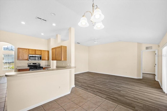 kitchen with decorative light fixtures, lofted ceiling, light hardwood / wood-style floors, kitchen peninsula, and stainless steel appliances