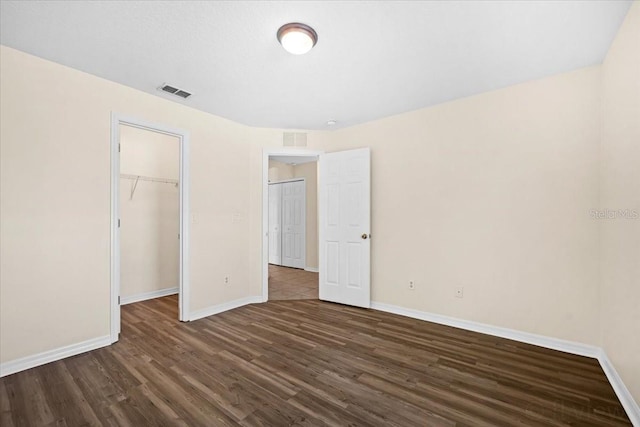 unfurnished bedroom featuring a closet, dark hardwood / wood-style floors, and a spacious closet