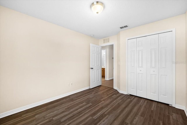 unfurnished bedroom with dark hardwood / wood-style flooring and a closet