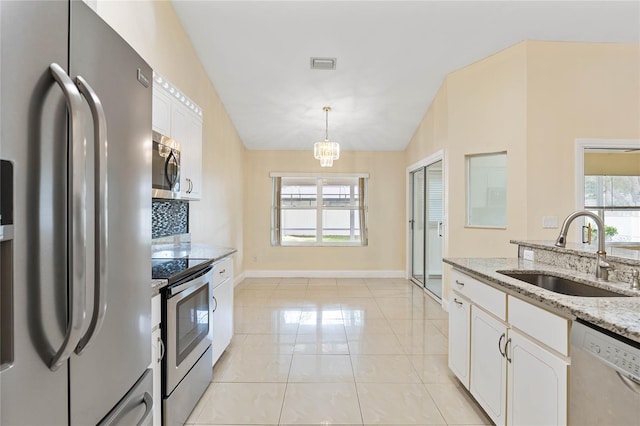 kitchen with a wealth of natural light, stainless steel appliances, sink, white cabinets, and lofted ceiling