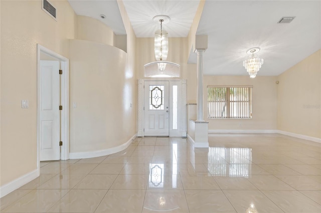 entrance foyer featuring light tile patterned flooring, decorative columns, and a chandelier