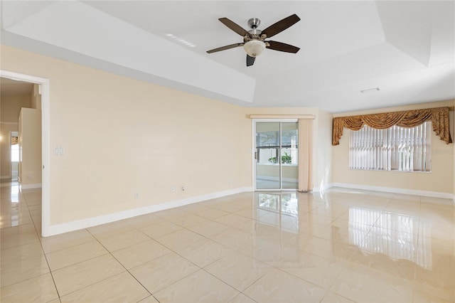 empty room featuring light tile patterned floors, a raised ceiling, and ceiling fan