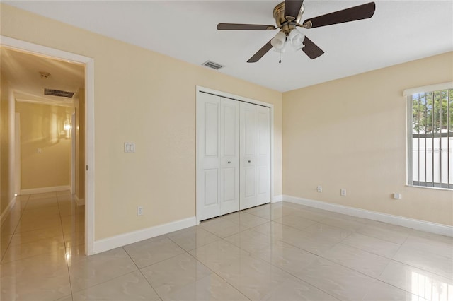 unfurnished bedroom with light tile patterned floors, a closet, and ceiling fan