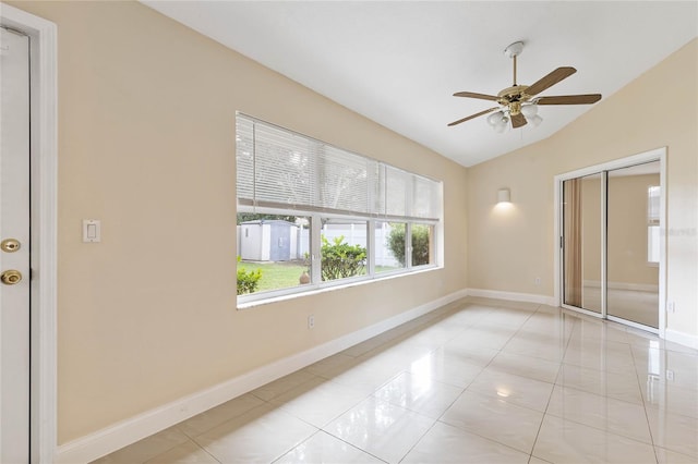 empty room featuring ceiling fan, light tile patterned floors, and lofted ceiling