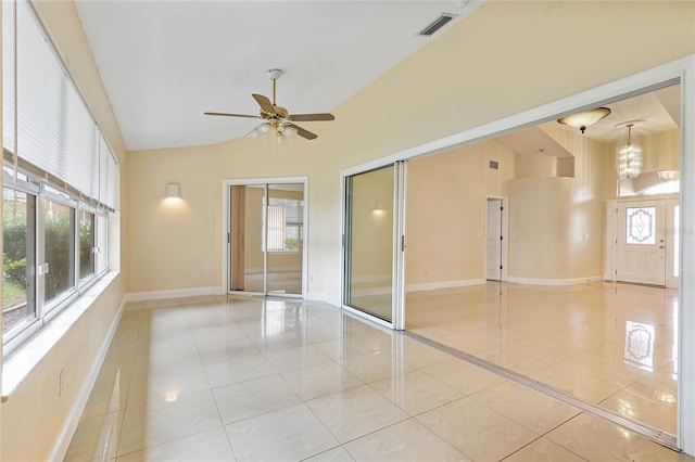 empty room featuring lofted ceiling, light tile patterned flooring, and ceiling fan with notable chandelier