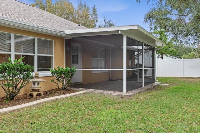 view of side of property with a sunroom, a yard, and a patio