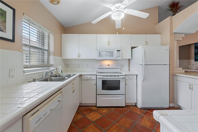 kitchen featuring lofted ceiling, white cabinetry, tile counters, and white appliances