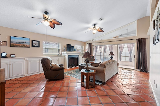 living room featuring tile patterned flooring, ceiling fan, a textured ceiling, and vaulted ceiling