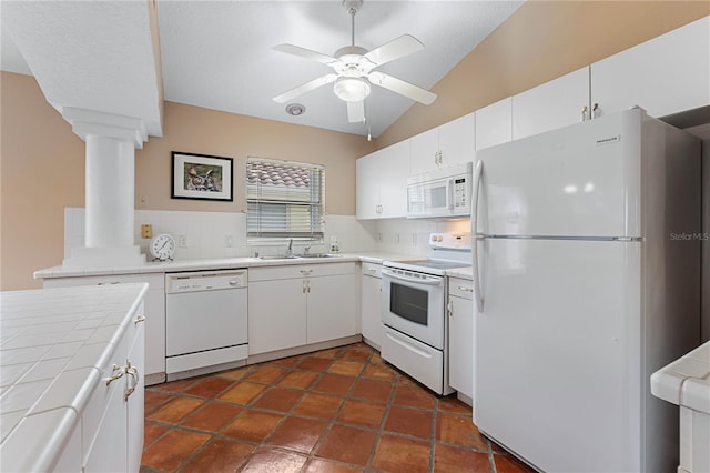 kitchen with backsplash, white appliances, vaulted ceiling, tile countertops, and white cabinets