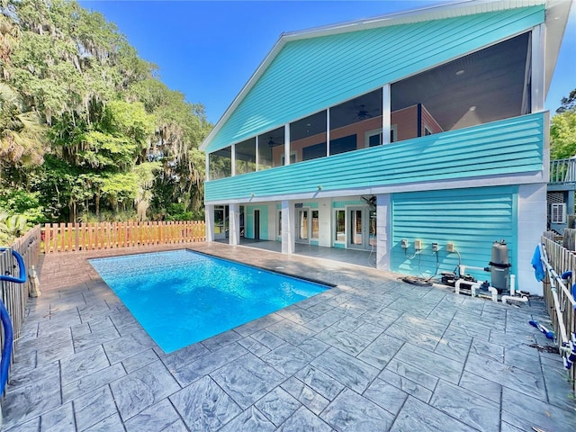 rear view of property with a fenced in pool, ceiling fan, a patio area, and a sunroom