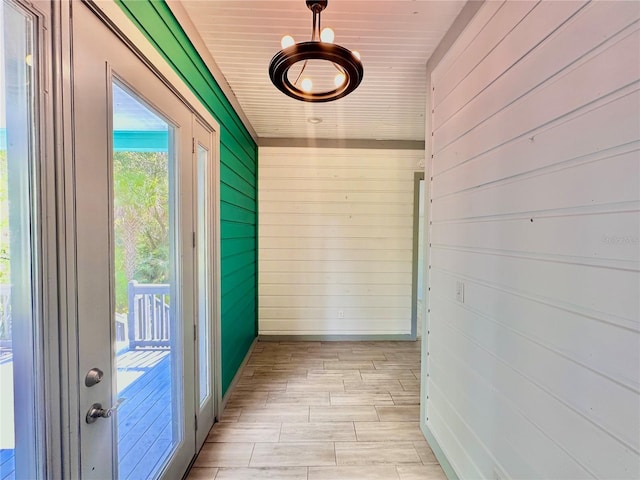 doorway with wood walls, light hardwood / wood-style floors, and wooden ceiling