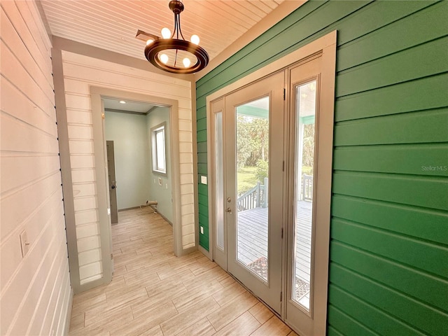 doorway to outside featuring light hardwood / wood-style floors, wood ceiling, and wooden walls