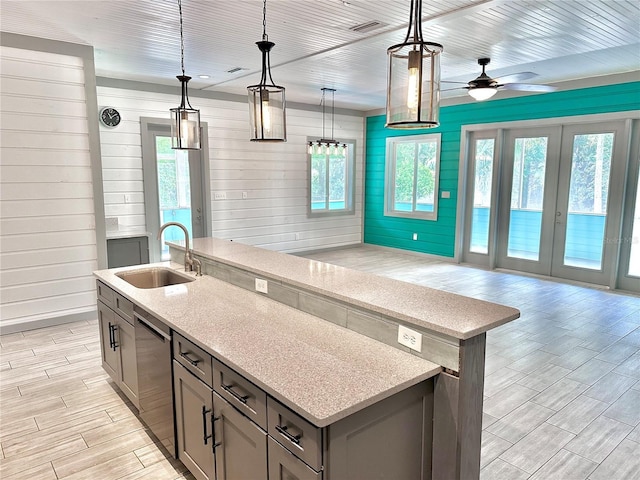 kitchen with ceiling fan, dishwasher, sink, an island with sink, and pendant lighting