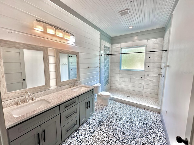 bathroom with tiled shower, vanity, and toilet