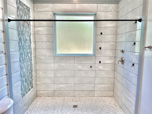 bathroom with a tile shower and toilet