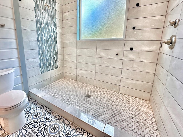 bathroom featuring tile patterned floors, toilet, and tiled shower