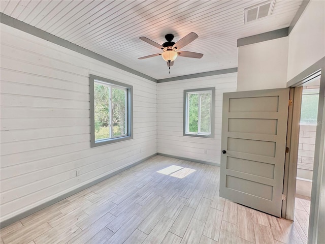 empty room with wood walls, light wood-type flooring, a healthy amount of sunlight, and wood ceiling