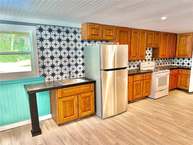 kitchen with electric range, light wood-type flooring, sink, and stainless steel refrigerator