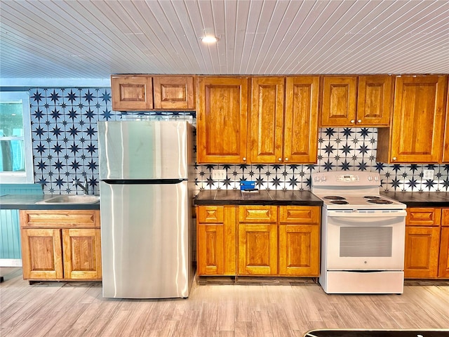 kitchen featuring stainless steel refrigerator, sink, light hardwood / wood-style flooring, white range with electric cooktop, and decorative backsplash