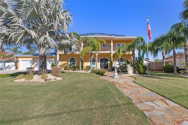 mediterranean / spanish home with solar panels, a balcony, a front yard, and a garage