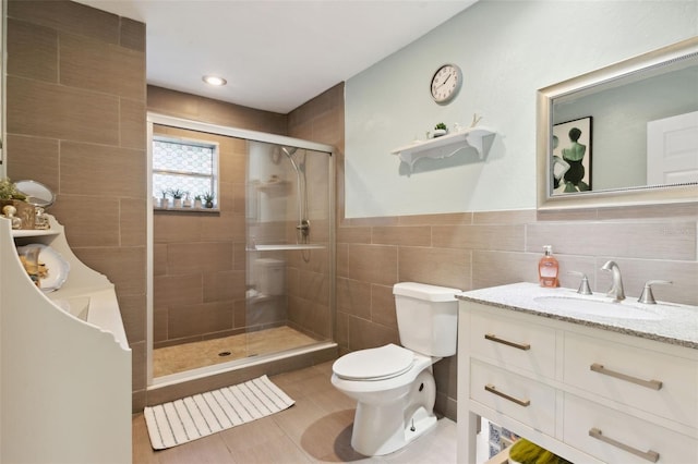 bathroom featuring tile patterned floors, an enclosed shower, toilet, vanity, and tile walls