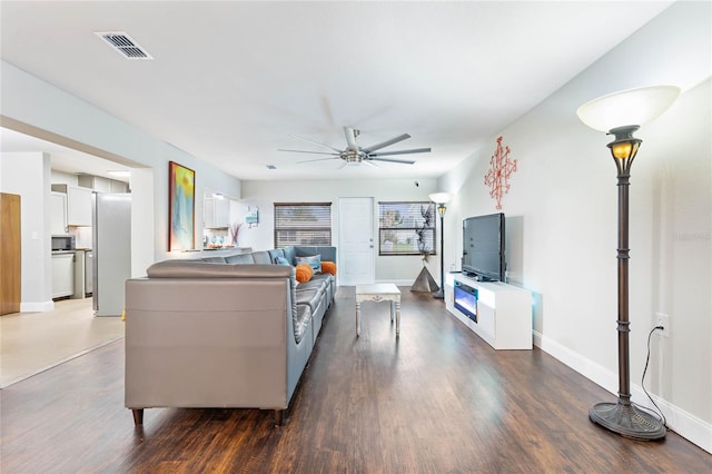 living room featuring dark hardwood / wood-style floors, ceiling fan, and a healthy amount of sunlight