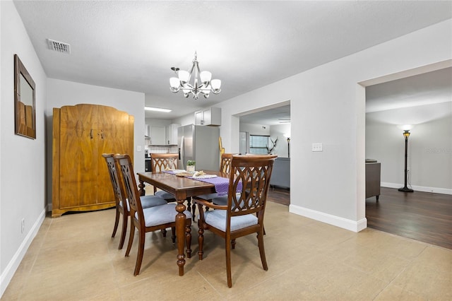 dining room featuring a textured ceiling, light hardwood / wood-style flooring, and a chandelier