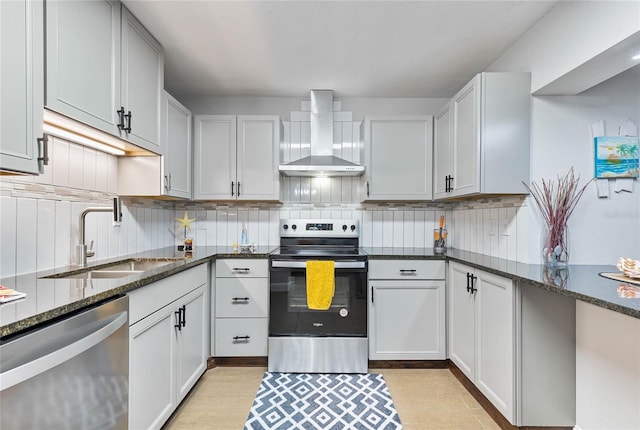 kitchen with sink, wall chimney range hood, stainless steel appliances, and dark stone counters