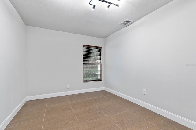 tiled spare room featuring a textured ceiling