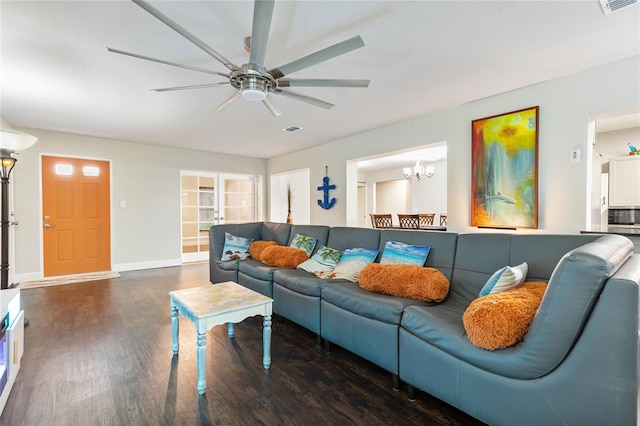 living room featuring ceiling fan with notable chandelier and dark wood-type flooring