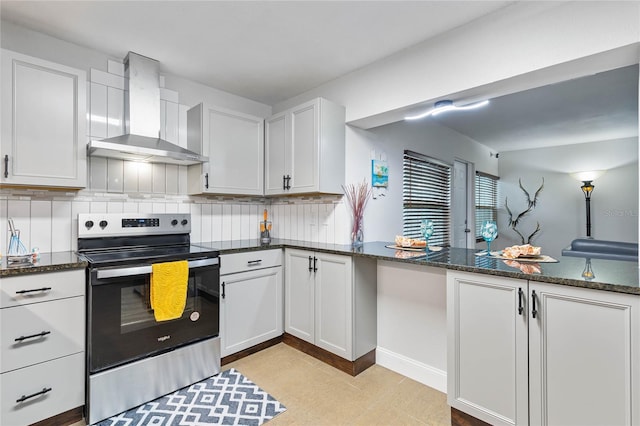 kitchen with white cabinets, electric range, wall chimney exhaust hood, dark stone countertops, and tasteful backsplash