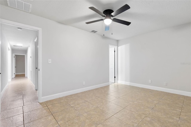 empty room with ceiling fan, light tile patterned flooring, and a textured ceiling