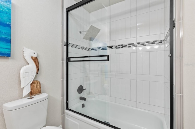 bathroom featuring toilet and combined bath / shower with glass door