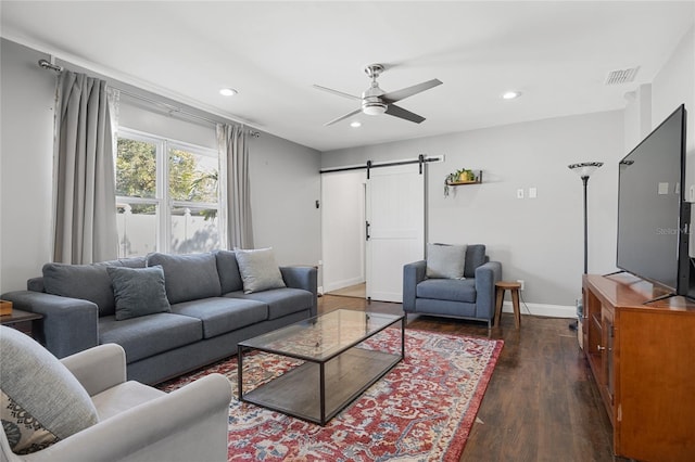 living room featuring a barn door, dark hardwood / wood-style floors, and ceiling fan