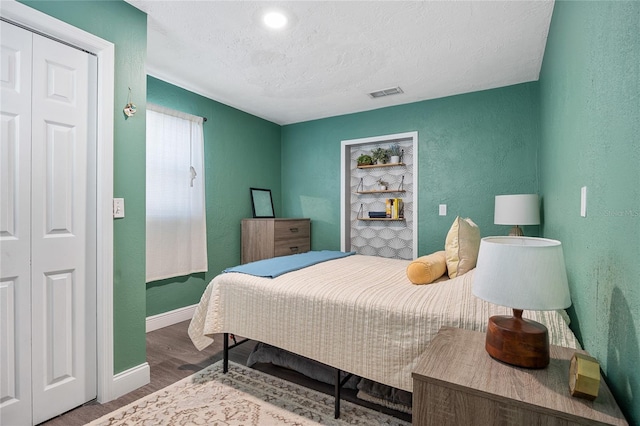 bedroom featuring wood-type flooring, a textured ceiling, and a closet