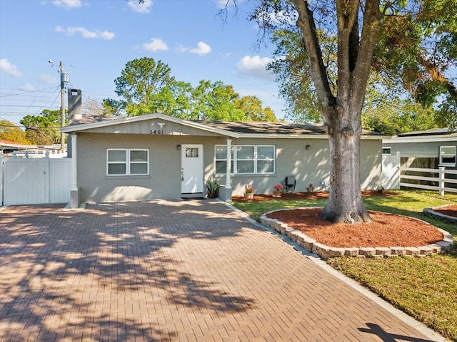 ranch-style home featuring fence and stucco siding