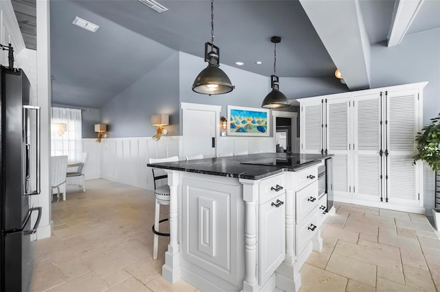 kitchen featuring a center island, hanging light fixtures, stainless steel fridge with ice dispenser, dark stone counters, and white cabinets