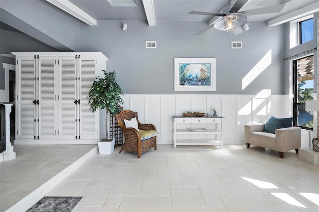 living area featuring beamed ceiling, ceiling fan, and light tile patterned flooring