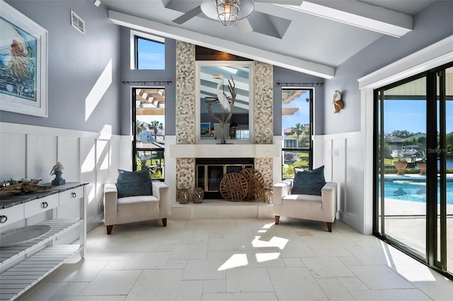 living area featuring vaulted ceiling with beams, ceiling fan, and a tiled fireplace