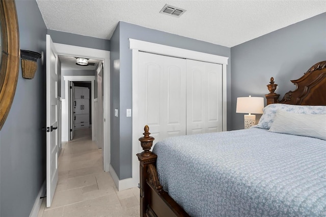 bedroom with a textured ceiling, a closet, and light tile patterned flooring