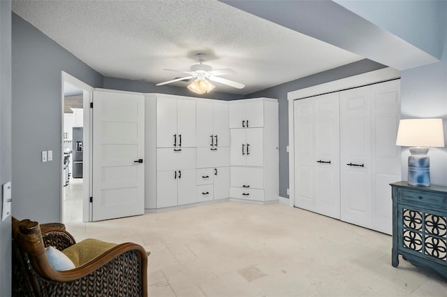 living area featuring ceiling fan and a textured ceiling