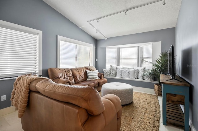 living room with light tile patterned floors, a textured ceiling, track lighting, and vaulted ceiling