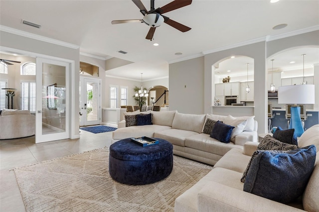 living room featuring light tile patterned floors, ceiling fan with notable chandelier, and ornamental molding