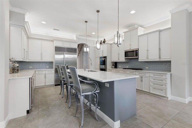 kitchen featuring decorative backsplash, an island with sink, appliances with stainless steel finishes, decorative light fixtures, and a kitchen bar