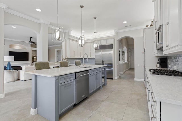 kitchen featuring sink, a kitchen island with sink, decorative light fixtures, decorative backsplash, and appliances with stainless steel finishes