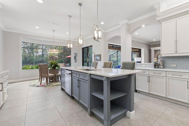 kitchen featuring decorative backsplash, decorative light fixtures, plenty of natural light, and a center island with sink