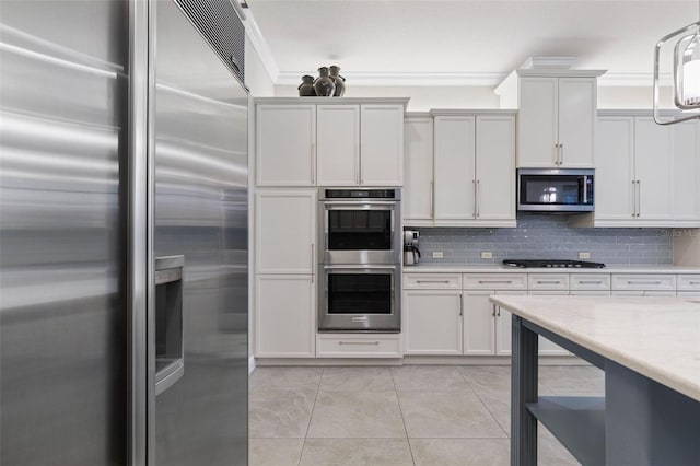 kitchen featuring hanging light fixtures, white cabinets, stainless steel appliances, and ornamental molding