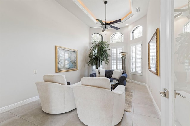 living area featuring ceiling fan, light tile patterned floors, and a tray ceiling