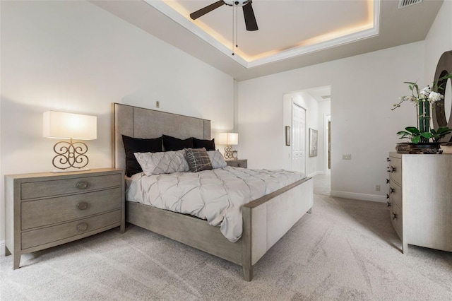 carpeted bedroom featuring ceiling fan and a tray ceiling