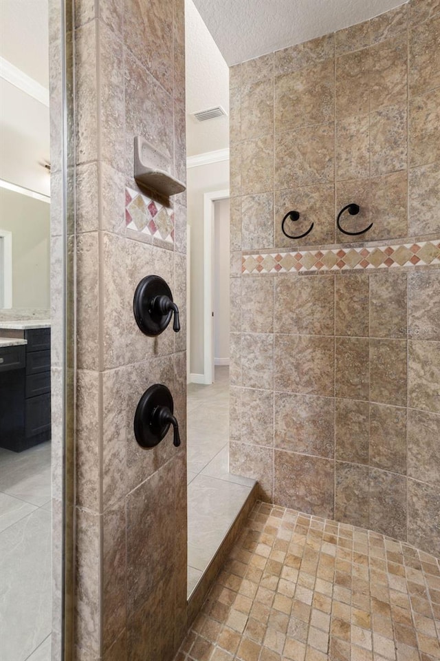 bathroom with tiled shower, crown molding, a textured ceiling, and vanity